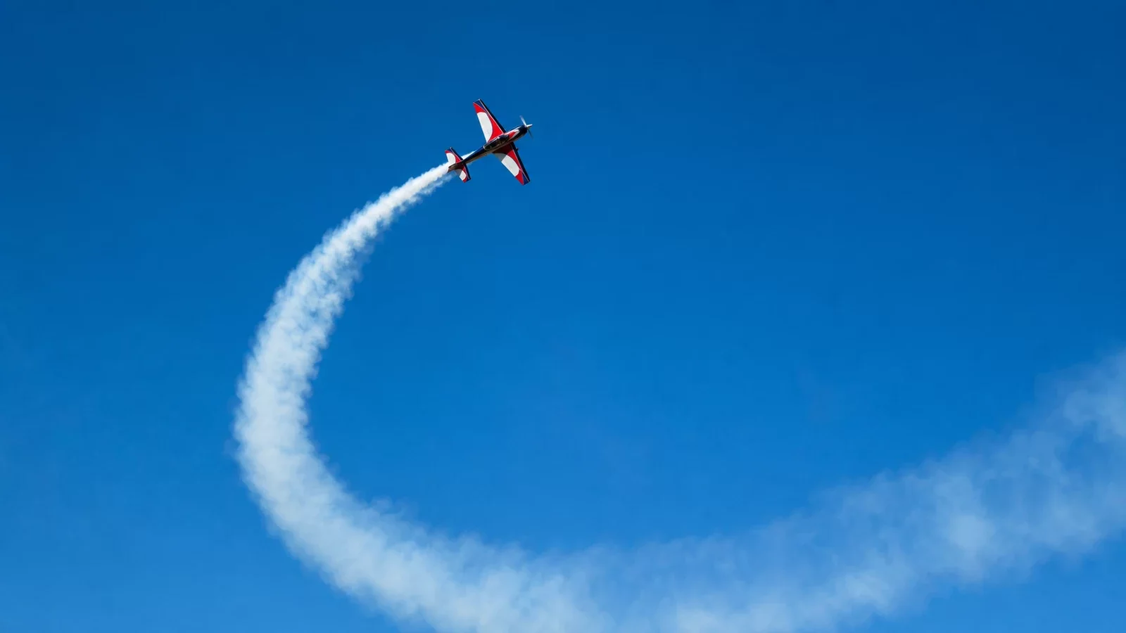 Avion télécommandé de voltige effectuant un looping dans un ciel bleu